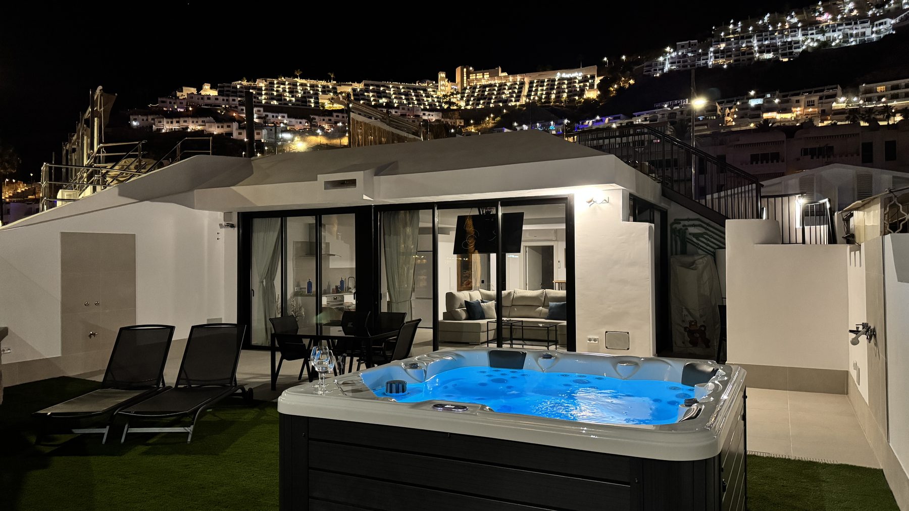 Sun, Sea & Love villa lit at night with the private jacuzzi and the illuminated hills of Puerto Rico behind