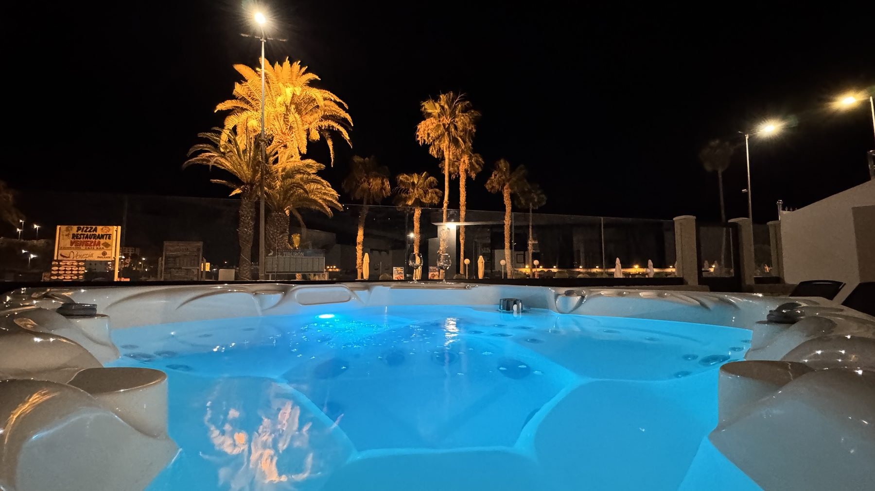 Private jacuzzi lit up at night with palms